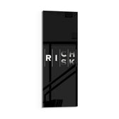 Minimalist black typography panel where the words "RISK" and "RICH" interlock in a single vertical column of white letters. panoramic glass wall art D