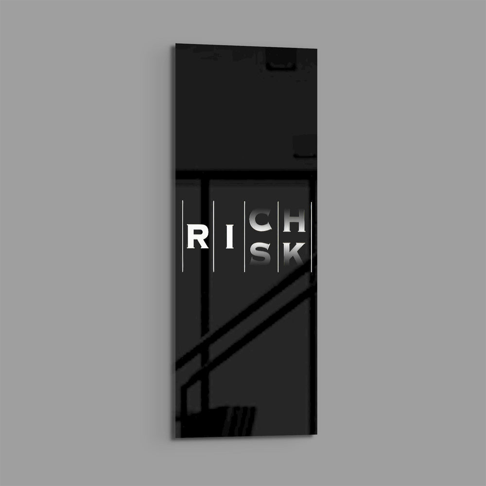 Minimalist black typography panel where the words "RISK" and "RICH" interlock in a single vertical column of white letters. panoramic glass wall art E