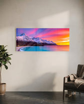 Snow-capped mountains under a vivid pink and orange twilight sky above a turquoise curving shoreline. panoramic glass wall art C