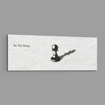 A single black chess pawn casting the long shadow of a king across a white textured surface, with a short motivational line of text panoramic glass wall art E