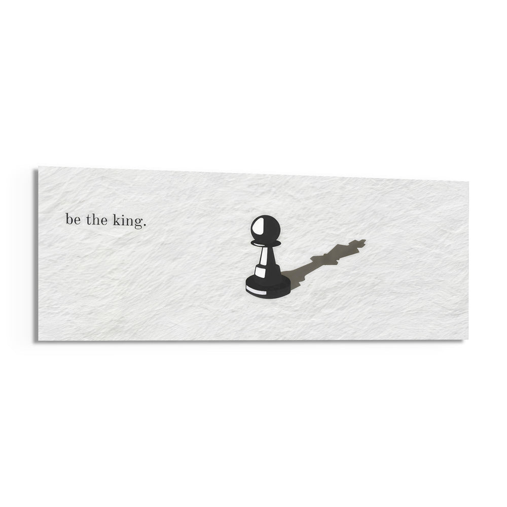 A single black chess pawn casting the long shadow of a king across a white textured surface, with a short motivational line of text panoramic glass wall art F