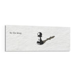 A single black chess pawn casting the long shadow of a king across a white textured surface, with a short motivational line of text panoramic glass wall art F