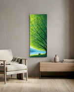 Two small figures sitting together on grass beneath a vast green tree, gazing over a calm blue lake toward distant mountains. panoramic glass wall art F