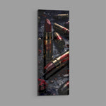 Dark, dramatic still life of crimson lipsticks shaped like brass cartridges, scattered with red lip prints, petals and water droplets. panoramic glass wall art E