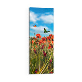 A sunlit meadow of red poppies and purple grape-hyacinth spikes with orange and green butterflies against a bright blue, cloud-dappled sky. panoramic glass wall art D