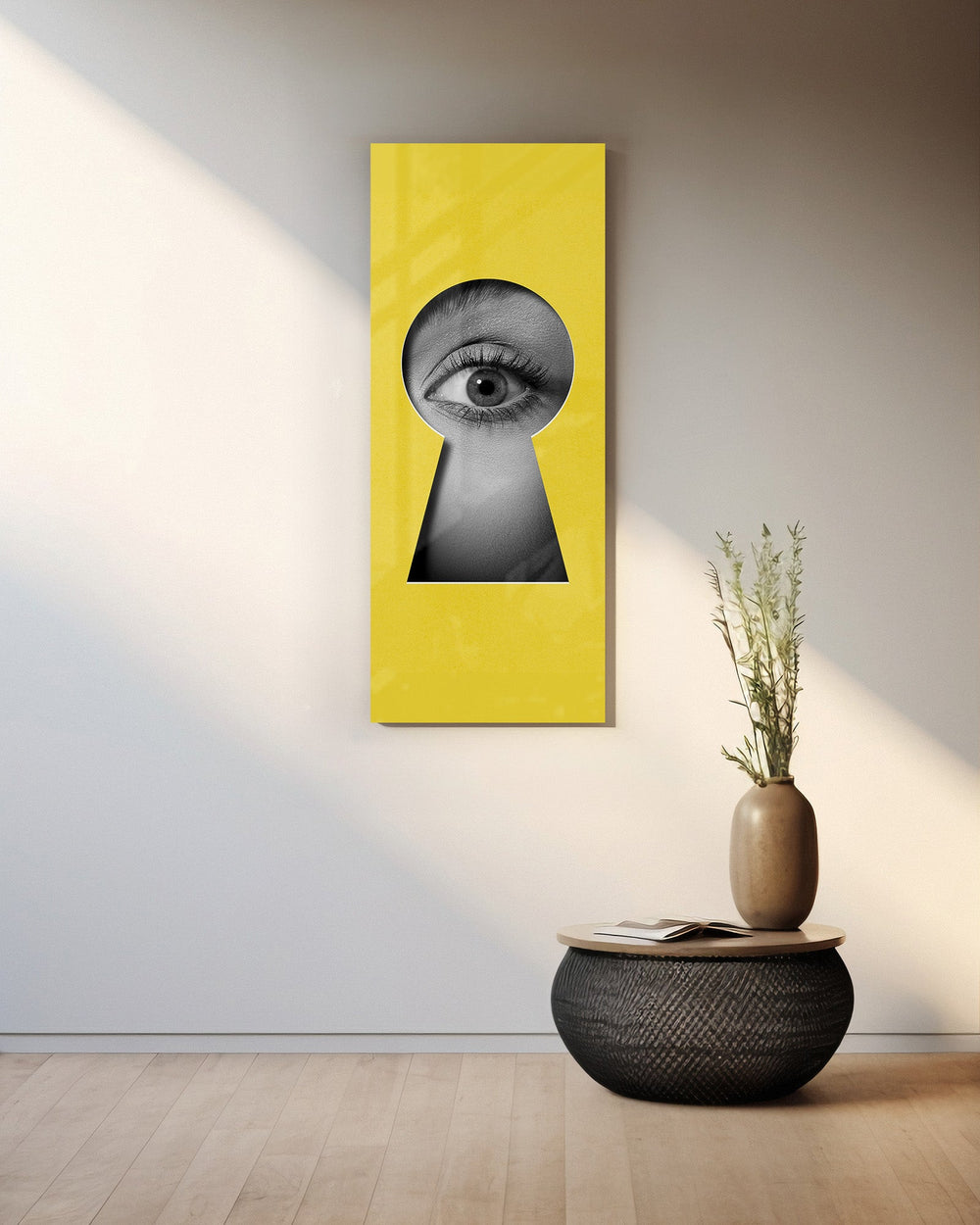 A black-and-white human eye peering out through a keyhole-shaped cutout in a flat, bright-yellow surface. panoramic glass wall art A