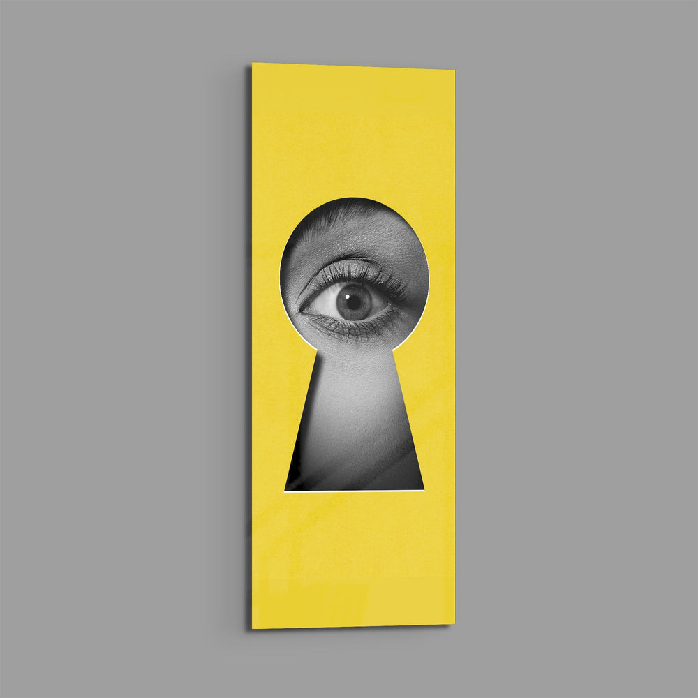 A black-and-white human eye peering out through a keyhole-shaped cutout in a flat, bright-yellow surface. panoramic glass wall art E