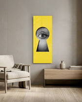 A black-and-white human eye peering out through a keyhole-shaped cutout in a flat, bright-yellow surface. panoramic glass wall art F