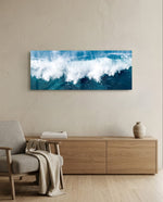A powerful ocean wave breaking into white foam and spray against deep teal and blue sea water. panoramic glass wall art A