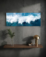 A powerful ocean wave breaking into white foam and spray against deep teal and blue sea water. panoramic glass wall art D