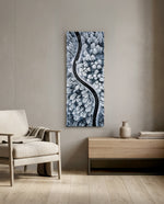 An aerial view of a dark, curving road snaking through a snow-covered pine forest in cool monochrome. panoramic glass wall art F