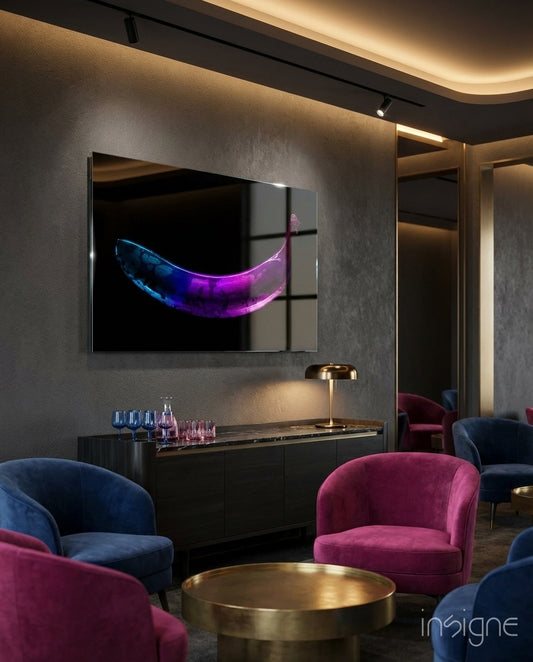 Neon Banana glass wall art displayed above a marble-topped console in a charcoal-walled lounge with magenta and navy chairs