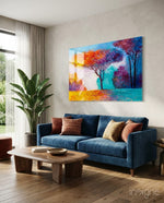 Autumn Pines glass wall art displayed above a blue velvet sofa in a bright contemporary living room