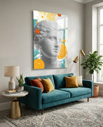 Venus Collage glass wall art displayed above a teal velvet sofa in a bright minimalist lounge