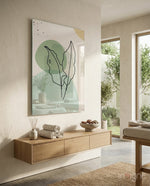 Sage Leaves glass wall art displayed above a wood floating console in a stone-walled spa bathroom