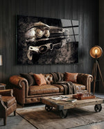 Vintage Cadillac glass wall art displayed above a brown chesterfield sofa in a dark wood-paneled lounge with brass tripod lamp
