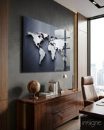Silver World Map glass wall art displayed above a walnut credenza in a dark brick-walled executive office with cognac chair