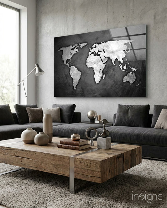 Grunge World Map glass wall art displayed above a charcoal sectional in a light concrete-walled lounge