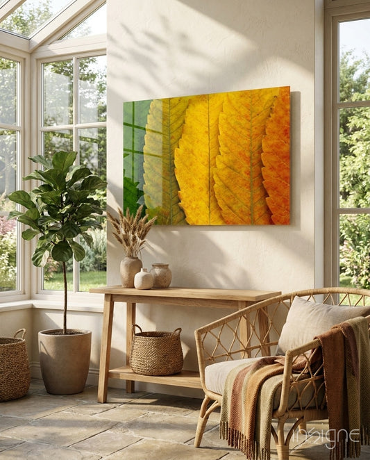 Autumn Leaves glass wall art displayed above a wood console in a bright sunroom with rattan chair