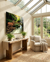 Forest Deer glass wall art displayed above a rustic wood console in a bright sunroom with bouclé chair