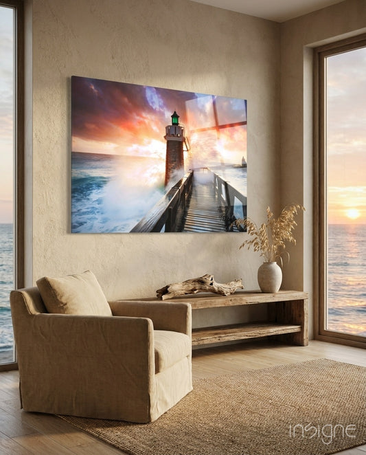 Sunset Lighthouse glass wall art displayed above a wood console in a warm beige coastal nook with linen chair