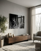 Night Trees glass wall art displayed above a walnut credenza in a warm minimalist living room with charcoal armchair