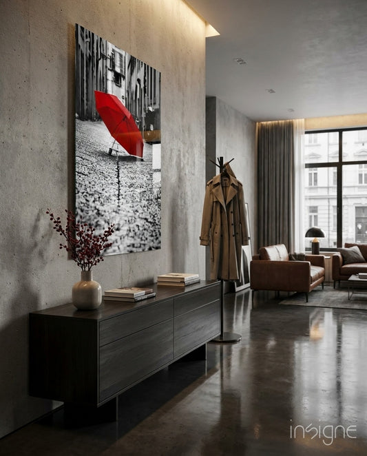 Red Umbrella glass wall art displayed above a wood console in an industrial concrete-walled hallway with brown leather sofa