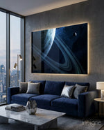 Ringed Saturn glass wall art displayed above a navy velvet sofa in a dark concrete-walled lounge with marble coffee table