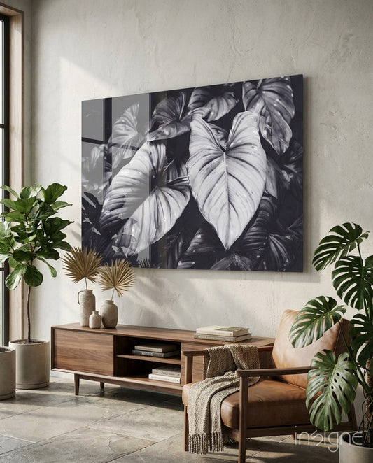 Monochrome Leaves glass wall art displayed above a walnut credenza in a warm minimalist concrete-walled lounge with cognac chair