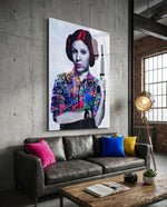 Leia Pop glass wall art displayed above a grey leather sofa in an industrial concrete-walled lounge with brass tripod lamp