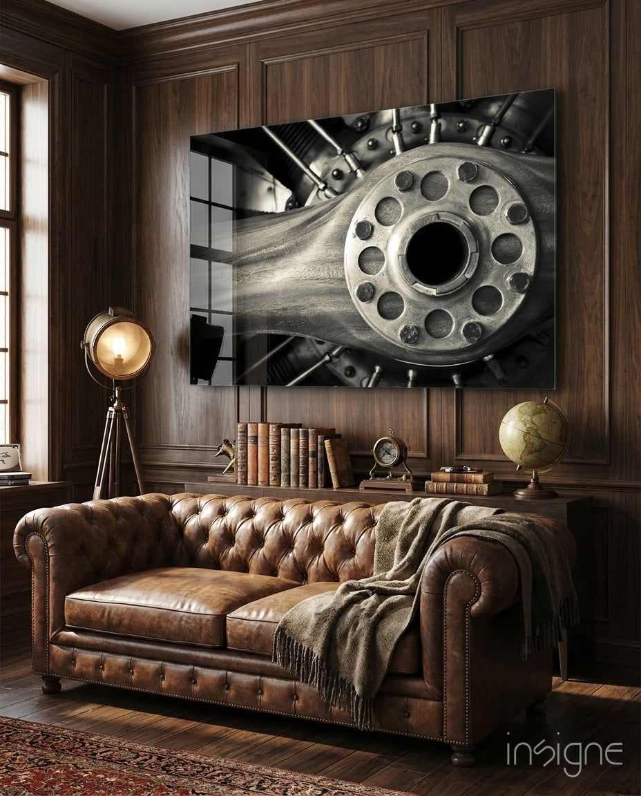 Vintage Engine glass wall art displayed above a brown chesterfield sofa in a dark wood-paneled lounge with brass tripod lamp