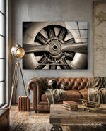 Vintage Propeller glass wall art displayed above a brown chesterfield sofa in an industrial stucco-walled lounge with map and brass tripod