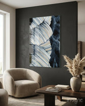 Abstract glass wall art displayed above a walnut coffee table in a moody charcoal-walled lounge with bouclé armchair and pampas vase