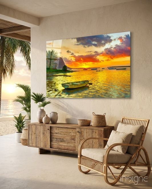 Sunset Fishing glass wall art displayed above a reclaimed wood console in a sand-toned outdoor patio with rattan armchair and palms