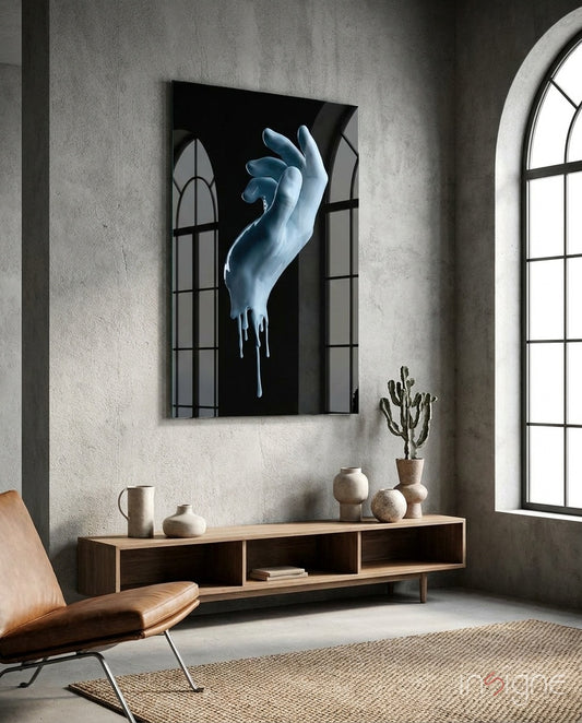 Hand glass wall art displayed above a walnut console in a concrete-walled lounge with arched windows and tan leather chair