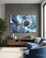 Abstract glass wall art displayed above a walnut credenza in a soft gray-walled lounge with navy velvet sectional and palm vase