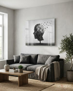 Autumn of Thoughts glass wall art displayed above a charcoal linen sofa in a soft white-plaster lounge with olive tree and stoneware vase