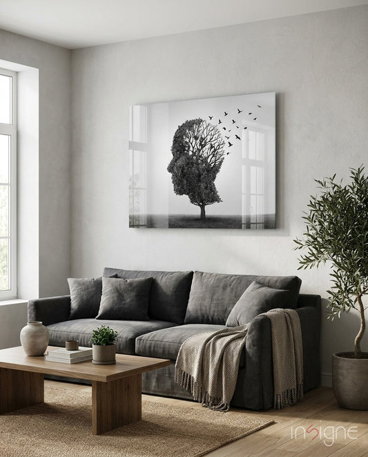 Autumn of Thoughts glass wall art displayed above a charcoal linen sofa in a soft white-plaster lounge with olive tree and stoneware vase