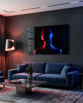 Women's glass wall art displayed above a navy velvet sofa in a moody charcoal-walled lounge with crimson lamp and dark drapes