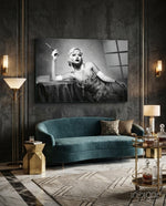 Roaring 20s glass wall art displayed above a teal velvet sofa in a paneled charcoal-walled lounge with brass sconces and marble floor