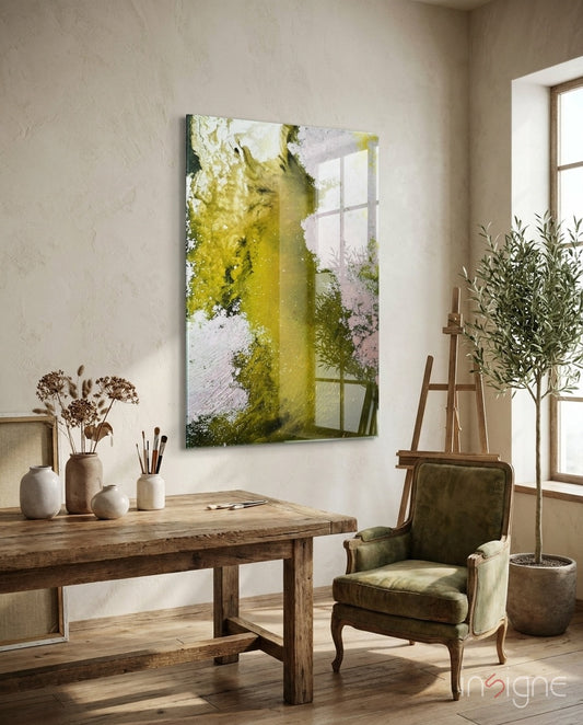Colors of Abstraction glass wall art displayed beside a wood easel in a soft cream-plaster artist studio with green velvet armchair and olive tree