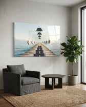 Loop glass wall art displayed above a charcoal linen armchair in a soft white-plaster lounge with round wood coffee table and fiddle leaf fig