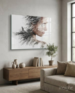 Woman Bird glass wall art displayed above a wood credenza in a soft white-plaster lounge with linen sofa and olive tree