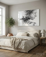 Woman Bird glass wall art displayed above a cream upholstered bed in a soft beige-plaster bedroom with olive tree and stoneware urn