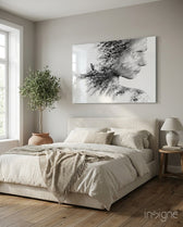 Woman Bird glass wall art displayed above a cream upholstered bed in a soft beige-plaster bedroom with olive tree and stoneware urn