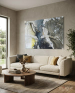 Marble glass wall art displayed above a bouclé sofa in a soft sand-plaster lounge with walnut coffee table and dried botanicals