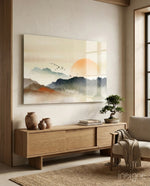 Abstract Landscape glass wall art displayed above a wood credenza in a soft cream-plaster lounge with linen armchair and bonsai