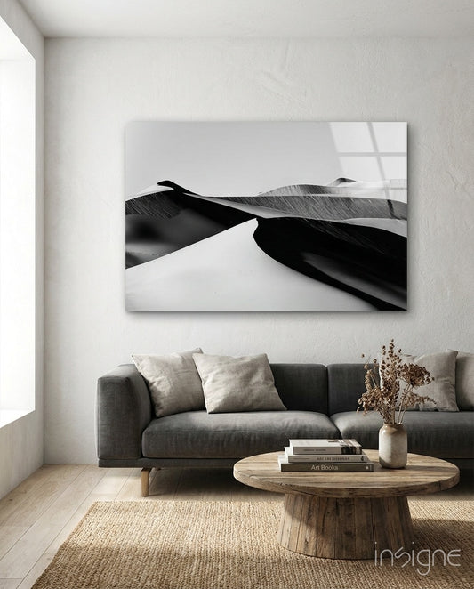 Black Landscape glass wall art displayed above a charcoal sofa in a soft white-plaster lounge with reclaimed wood coffee table and dried botanicals