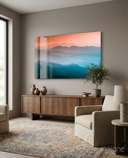 Abstraction glass wall art displayed above a walnut credenza in a soft taupe-walled lounge with linen armchair and olive tree