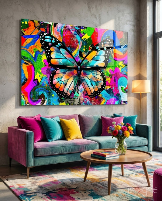 Butterfly glass wall art displayed above a teal velvet sofa in a soft concrete-walled lounge with magenta velvet pillows and round wood coffee table